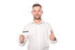 © Igor - smiling businessman holding credit card and showing thumb up isolated on white