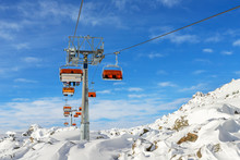 Ski Lift Ropeway On Hilghland Alpine Mountain Winter Resort On Bright Sunny Day. Ski Chairlift Cable Way With People Enjoy Skiing And Snowboarding. Downhill Slopes And Virgin Snow Off-piste Area