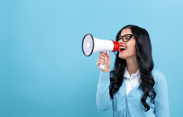 Wall Mural - Young woman with a megaphone on a blue background