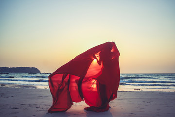 Wall Mural - Creature in a red floaty robe standing on the beach sunset golden hour silhouette Ngapali beach Myanmar