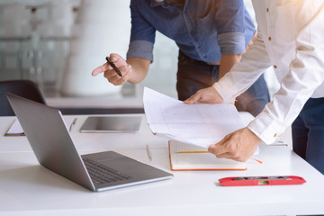 Architects,engineer team discussing together on a paper blueprint and laptop for new construction project planning in modern office. Architects,engineer brainstorming concept.