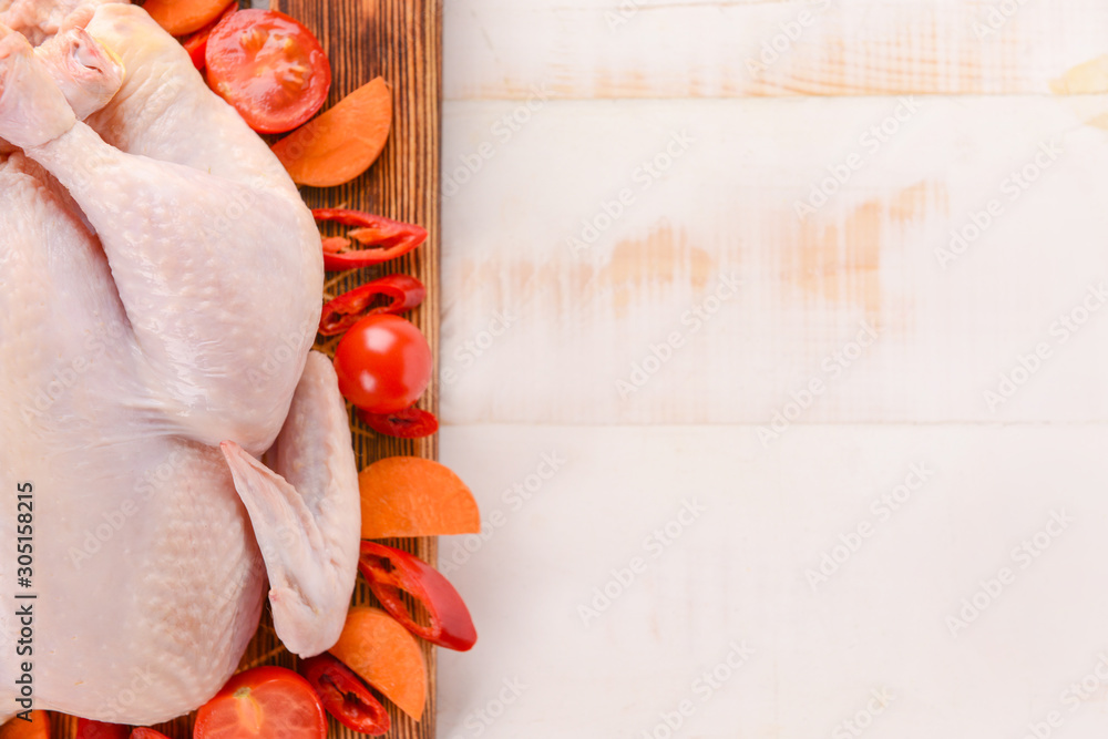 Raw chicken with chili and tomato on wooden background