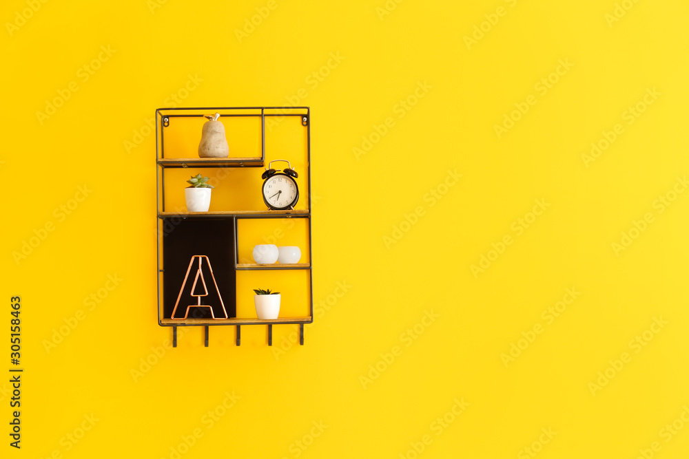 Shelves with decor hanging on color wall