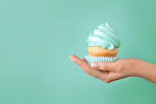 Female Hand With Tasty Cupcake On Turquoise Background