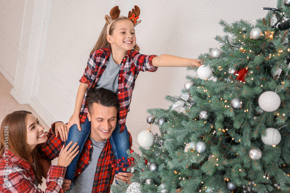 Happy family decorating Christmas tree at home