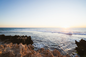 Wall Mural - The beautiful view of Trigg beach at sunset over the jagged rocks, ocean and beach on a lovely evening in Perth, Western Australia. 