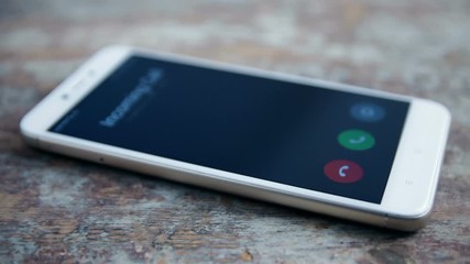 incoming call on white mobile phone on wooden surface