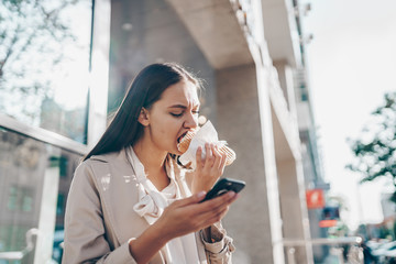 the student is hungry and bites the pie with hungry greed while looking at the phone