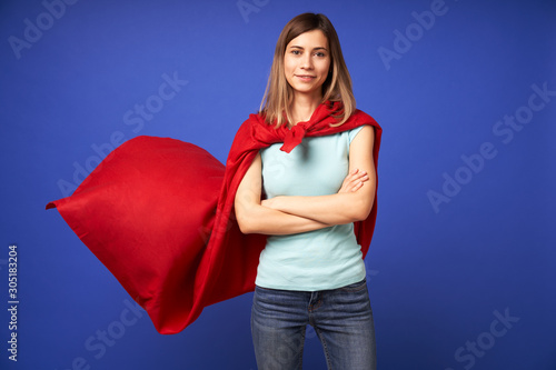 Fotografía Woman in red superhero cloak standing on empty blue background