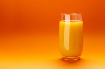 Glass of orange juice isolated on orange background with copy space