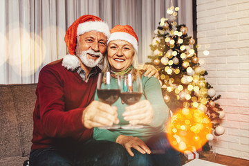 Happy and funny senior couple drinking wine and celebrating New Year in their home.