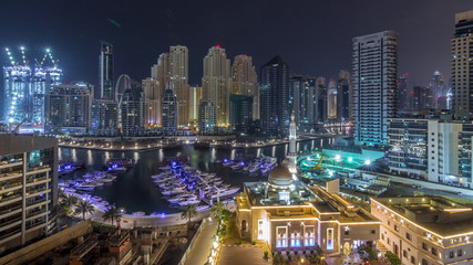 Wall Mural - Yachts in Dubai Marina flanked by the Al Rahim Mosque and residential towers and skyscrapers aerial night timelapse.