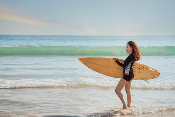 View of beautiful sexy young woman surfer girl  with yellow surfboard on a beach at sunset or sunrise.Young asian surfer woman. Good holiday vacation summer concept.