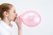 Caucasian woman blowing a balloon 