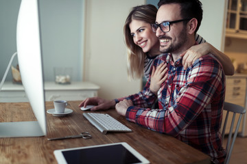 Young couple of designers working on computer