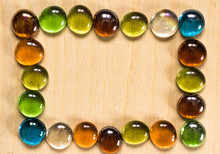 Frame Lined With Glass Pebbles On A Wooden Background. Colorful Lollipops On A Wooden Table