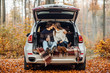© Тарас Нагирняк - Beautiful couple enjoying picnic time on the forest. They drinking tea and sitting in a car.