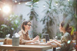 © Seventyfour - Side view portrait of two modern young women sitting at table in cafe and smiling cheerfully enjoying lunch together, copy space