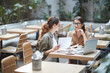 © Seventyfour - Portrait of two young businesswomen discussing project while sitting at table in designer cafe, copy space