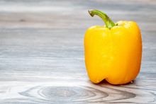 Yellow Bell Pepper With Water Drops On It On A Wooden Surface