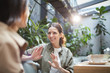 © Seventyfour - Waist up portrait of smiling young woman talking to friend on outdoor cafe terrace, copy space