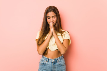 Young slim woman holding hands in pray near mouth, feels confident.