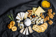 Assortment of French cheese with honey, nuts and figs on cutting board. Black background. Top view