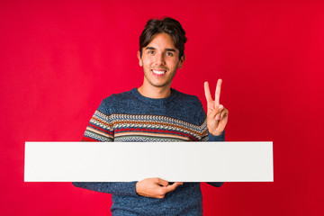 Young man holding a placard showing number two with fingers.