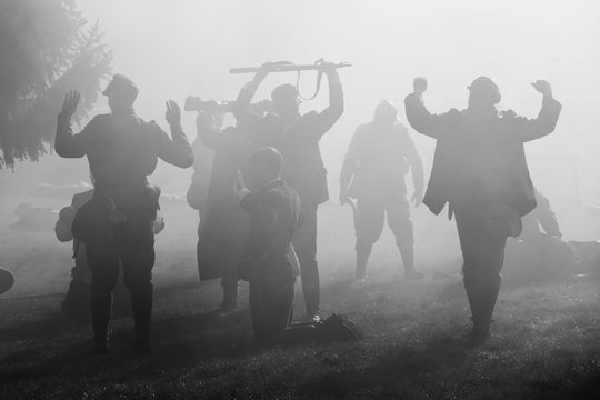 silhouettes of soldiers in uniforms during war with rifles on battlefield. all area is in smoke and 