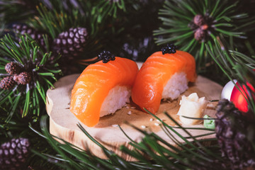 Sushi nigiri set with salmon on wooden board. Christmas or New Year concept background. Tree branch with gifts. Traditional japanese food. Close up view