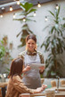 © Seventyfour - Portrait of smiling young waitress holding digital tablet while taking orders at outdoor cafe terrace lit by warm sunlight