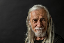 Low Key Portrait Of Attractive Long Gray Hair Old Man Looking At Camera With Tranquility. 