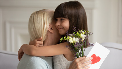 Wall Mural - Granddaughter felicitates grandmother with birthday gave flowers and card