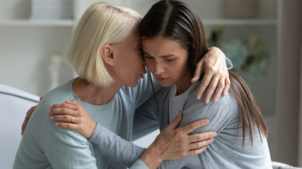 Wall Mural - 50s mother hugs calms grownup daughter telling words supporting her