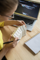 Canvas Print - Young female architect working over new residence model in front of laptop