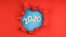 Year 2020 Written In Wooden Numbers Or Letters On A Blue Background. In The Hole From The Red Background