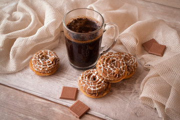 Conceptual coffee morning image, cup of black coffee with beige cookies and chocolate. Symbolic image. Wooden shabby background.