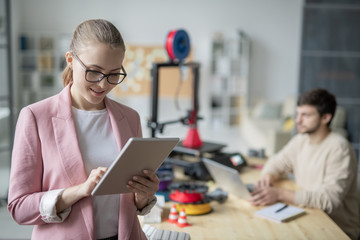 Canvas Print - Young elegant businesswoman scrolling in tablet while searching for online data