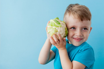 Wall Mural - Little Boy Holding Broccoli in his hands on blue background, diet and exercise for good health concept