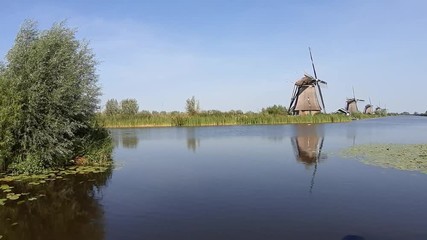 Wall Mural - Kinderdijk, Netherlands. August 2019. The mills of this small town are one of Holland's attractions. Enchanting view of one of the canals with the mills lined up along the bank. Pan 30fps movement.