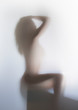 Beautiful and sexy long hair woman sits and poses behind a bathroom curtain. Only body silhouette can be seen.