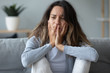 © fizkes - Closeup of female sitting on couch looking unhappy and desperate