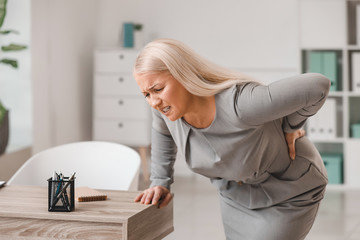 Sticker - Mature woman suffering from back pain in office