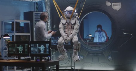 astronaut moving limbs while hanging on bands