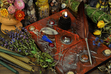 Still life with magic book, black candle, quill, herbs and elixir on witch table.