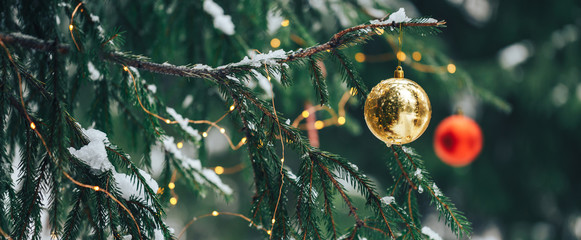 Wall Mural - decorated christmas tree with red and gold balls on blurred, sparkling background, outdoor.