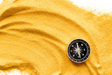 Wall Mural - Travel concept. Compass on yellow sand background top view copy space
