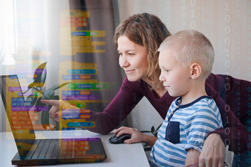 young programmer writing code on a computer together with his mom or teacher. programming lessons fo