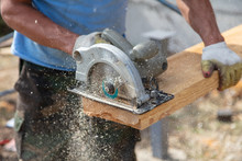 A Worker Cuts A Wooden Beam At A Construction Site