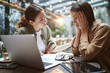 © Seventyfour - Side view portrait of frustrated young woman working at table in cafe with friend or colleague comforting her, copy space